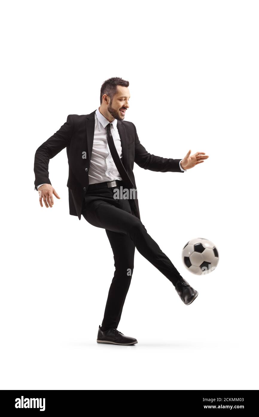 Ganzkörperaufnahme eines Mannes in Anzug und Krawatte Tritt einen Fußball isoliert auf weißem Hintergrund Stockfoto