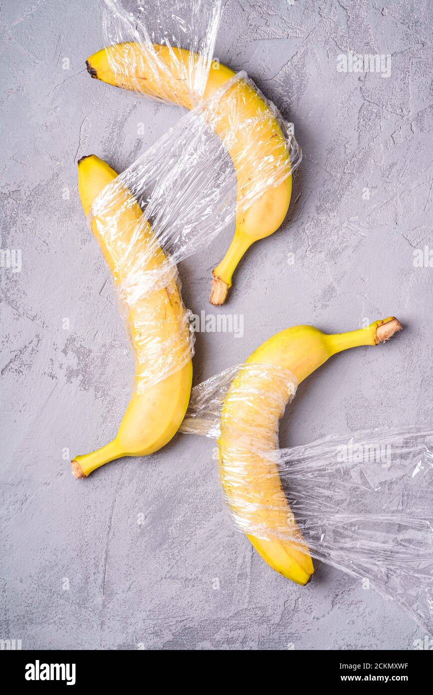 Banane Obst in Stretch-Wrap-Kunststoff auf Stein Beton Hintergrund eingewickelt, kreative Layout, Ökologie und Umwelt-Konzept Stockfoto