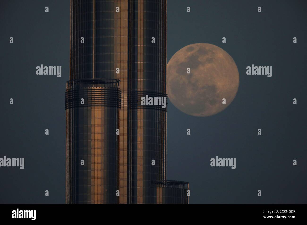 Vor dem 'Super Pink Moon' in Dubai, Vereinigte Arabische Emirate, am 7. April 2020, erhebt sich hinter dem Burj Khalifa, dem höchsten Gebäude der Welt, ein wachender, wuchtiger Mond. REUTERS/Christopher Pike Stockfoto