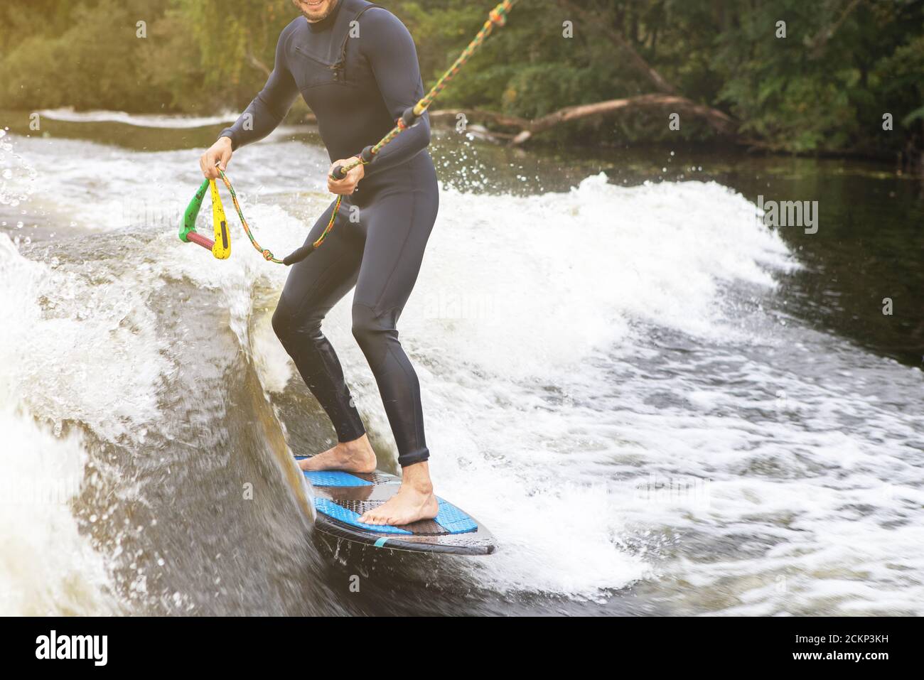 Unkenntlich fit kaukasischen Mann reitet wecken Brandung auf Fluss oder See am Abend in der untergehenden Sonne. Konzept für Wassersport, Urlaub und Wochenendaktivitäten. Stockfoto