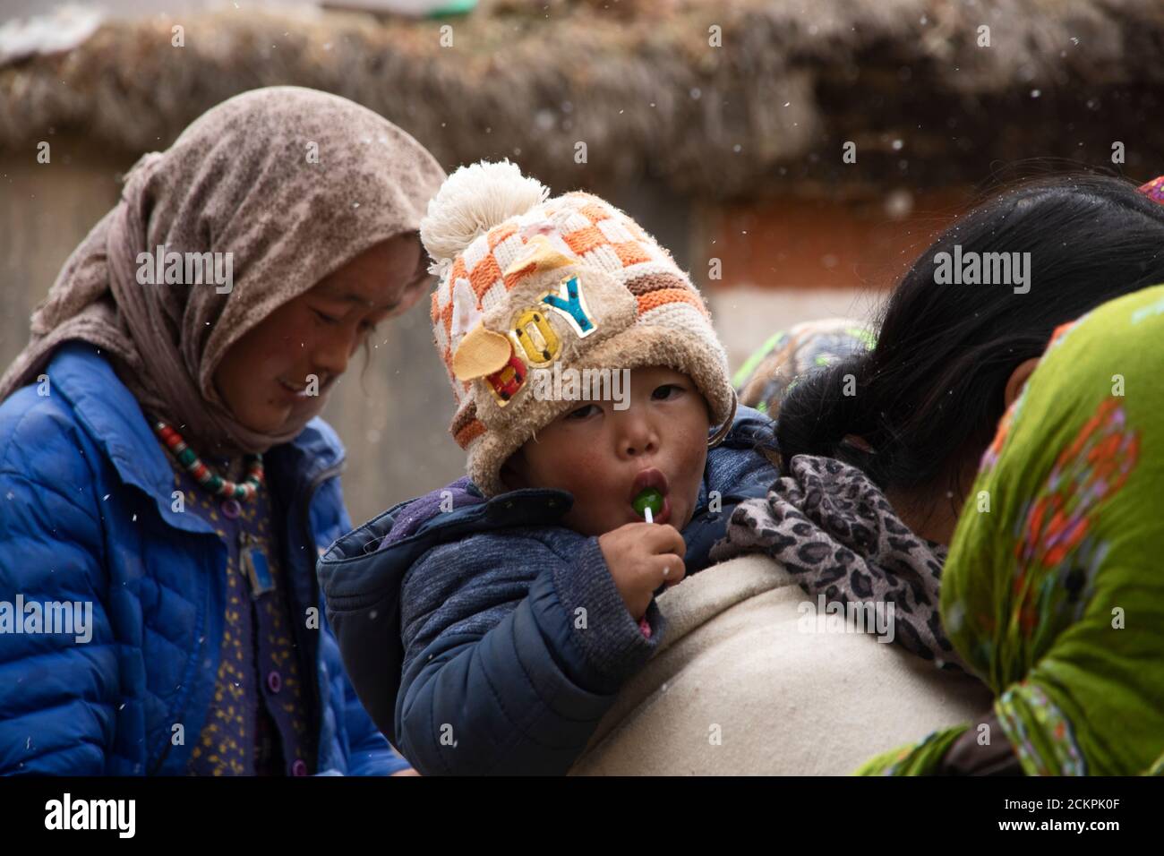 Fröhliche Menschen im Murdorf, dem letzten Dorf des Pin Valley an einem verschneiten Tag, versammeln sich auf einem Marktplatz. Eine Mutter trägt ihr Kind. Stockfoto