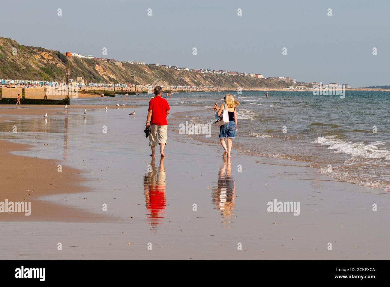 Boscombe, Bournemouth, Dorset, UK, 16. September 2020, Wetter. Menschen am Strand und im Meer genießen den dritten Tag der September Hitzewelle mit heißem Sonnenschein am Nachmittag. Ein Paar geht am Ufer entlang auf nassem Sand. Kredit: Paul Biggins/Alamy Live Nachrichten Stockfoto