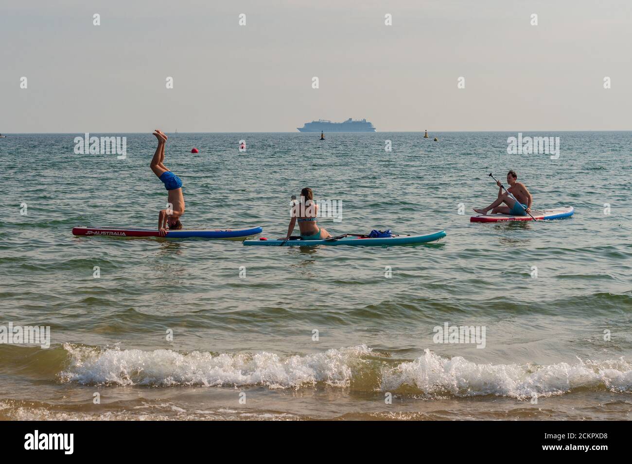 Boscombe, Bournemouth, Dorset, UK, 16. September 2020, Wetter. Menschen am Strand und im Meer genießen den dritten Tag der September Hitzewelle mit heißem Sonnenschein am Nachmittag. Ein Paddleboarder versucht Akrobatik auf seinem Brett und versucht einen Handstand. Kredit: Paul Biggins/Alamy Live Nachrichten Stockfoto