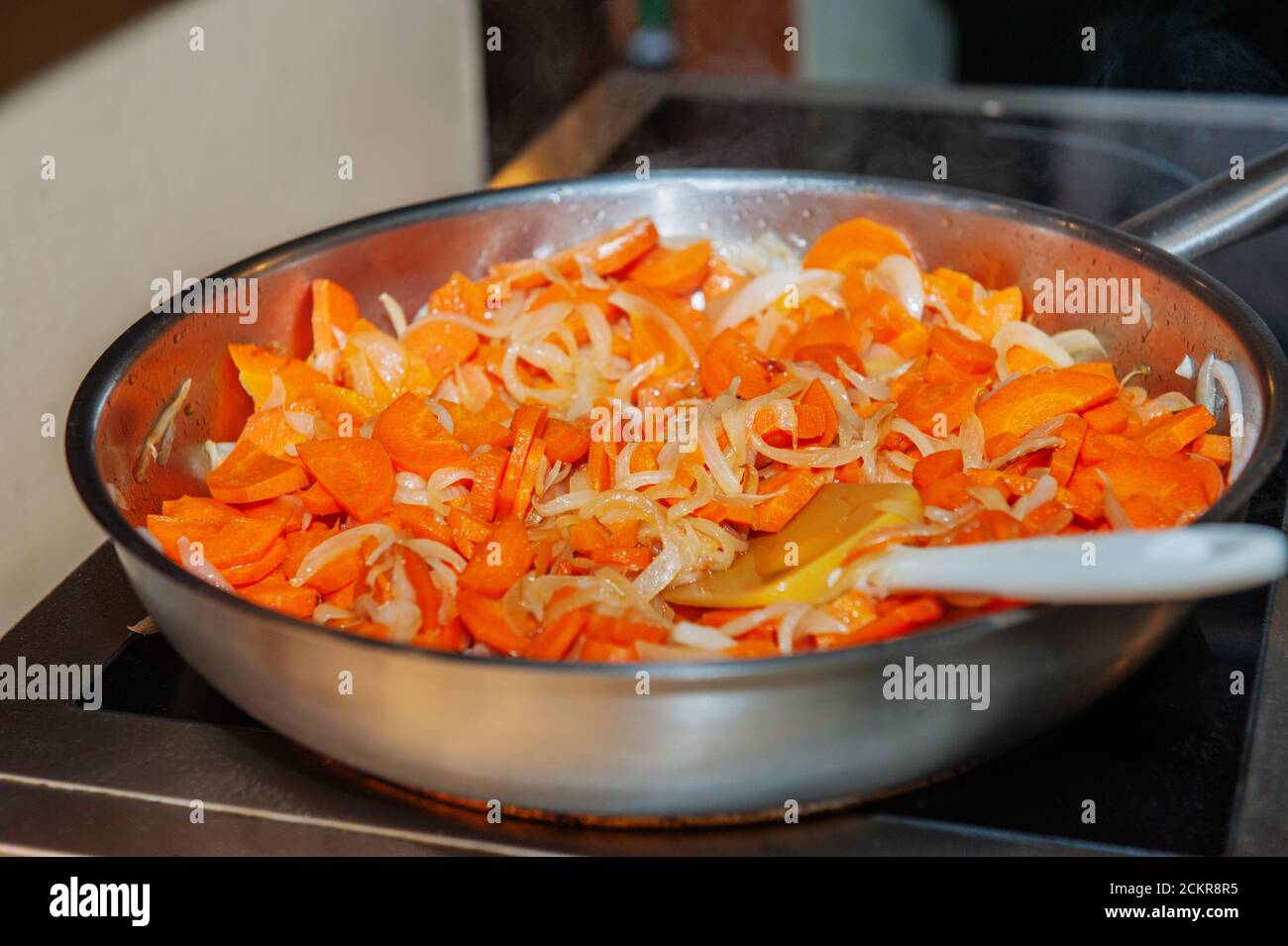 Geschmortes Gemüse. In einer großen Pfanne Karotten mit Zwiebeln und Gemüse  anbraten. Kochen in einem Restaurant Stockfotografie - Alamy