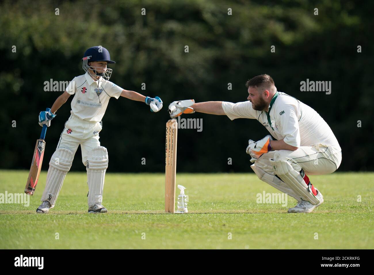 Junger Batsman und Erwachsener Wicket Keeper Faustschlag während Dorf Cricket Tatsache für alle Altersgruppen. Stockfoto