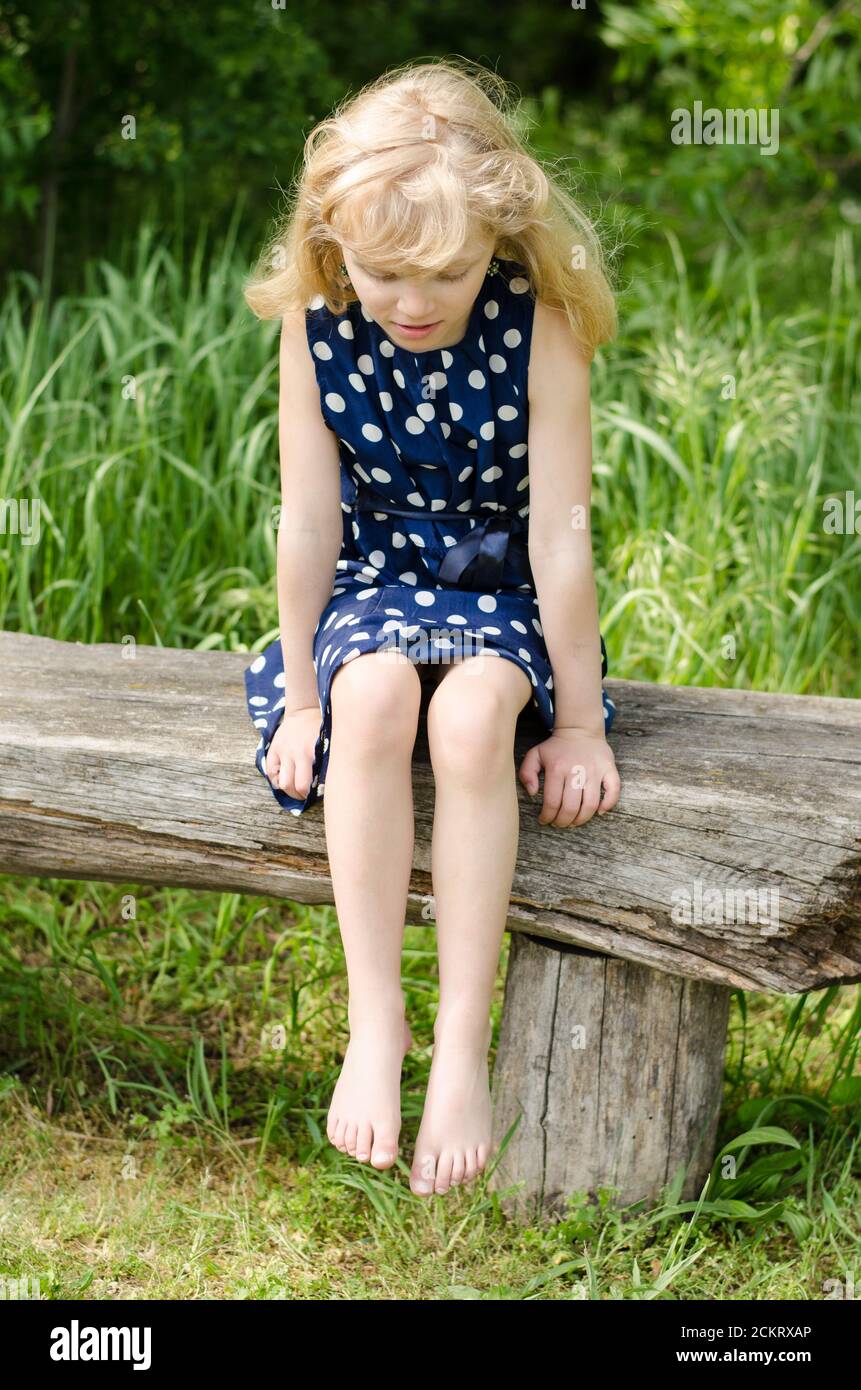 Trauriges Mädchen mit langen blonden Haaren sitzt in Bank und Warten Stockfoto