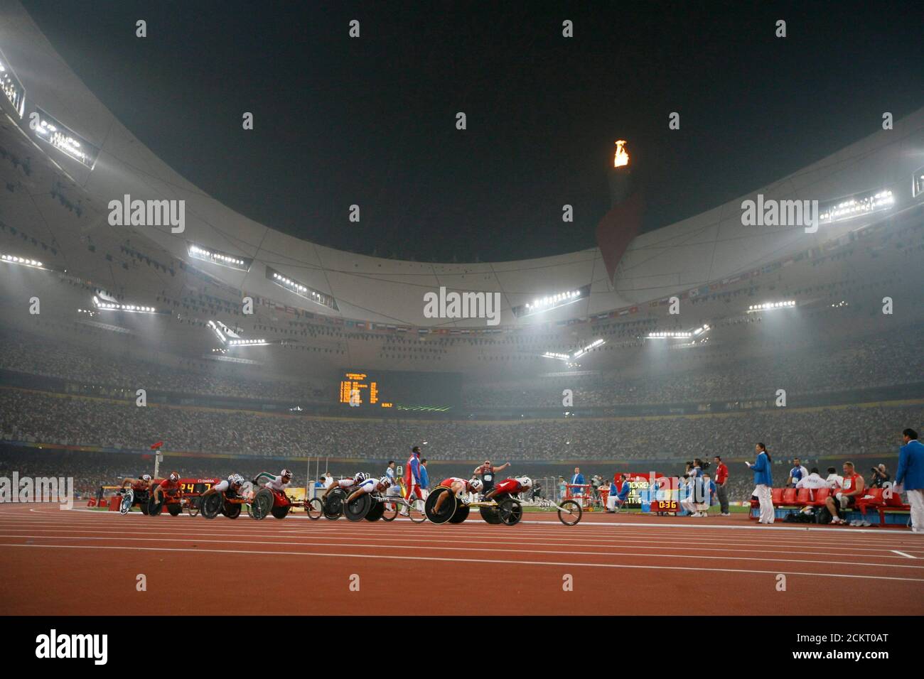 Peking, China, 15. September 2008: Szenen aus einer Abendveranstaltung der Paralympischen Spiele im Olympiastadion, bekannt als Vogelnest. Rollstuhlfahrer auf der 5000 Meter langen Strecke an einem rauchigen Pekinger Abend während der Paralympics. ©Bob Daemmrich Stockfoto