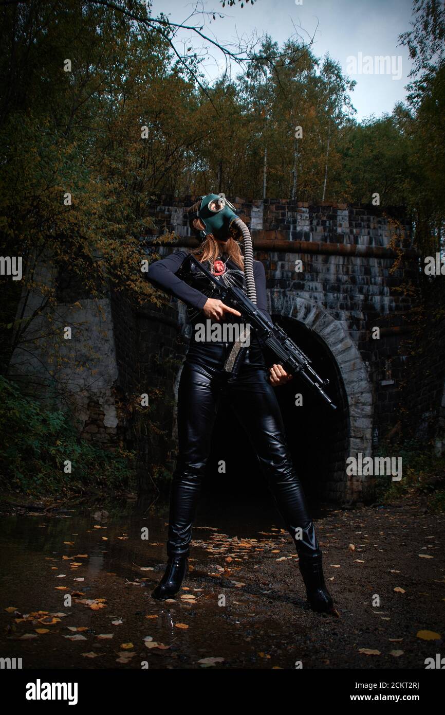 Eine Frau in einem schwarzen Anzug und Gasmaske mit einem Maschinengewehr in den Händen. Stockfoto