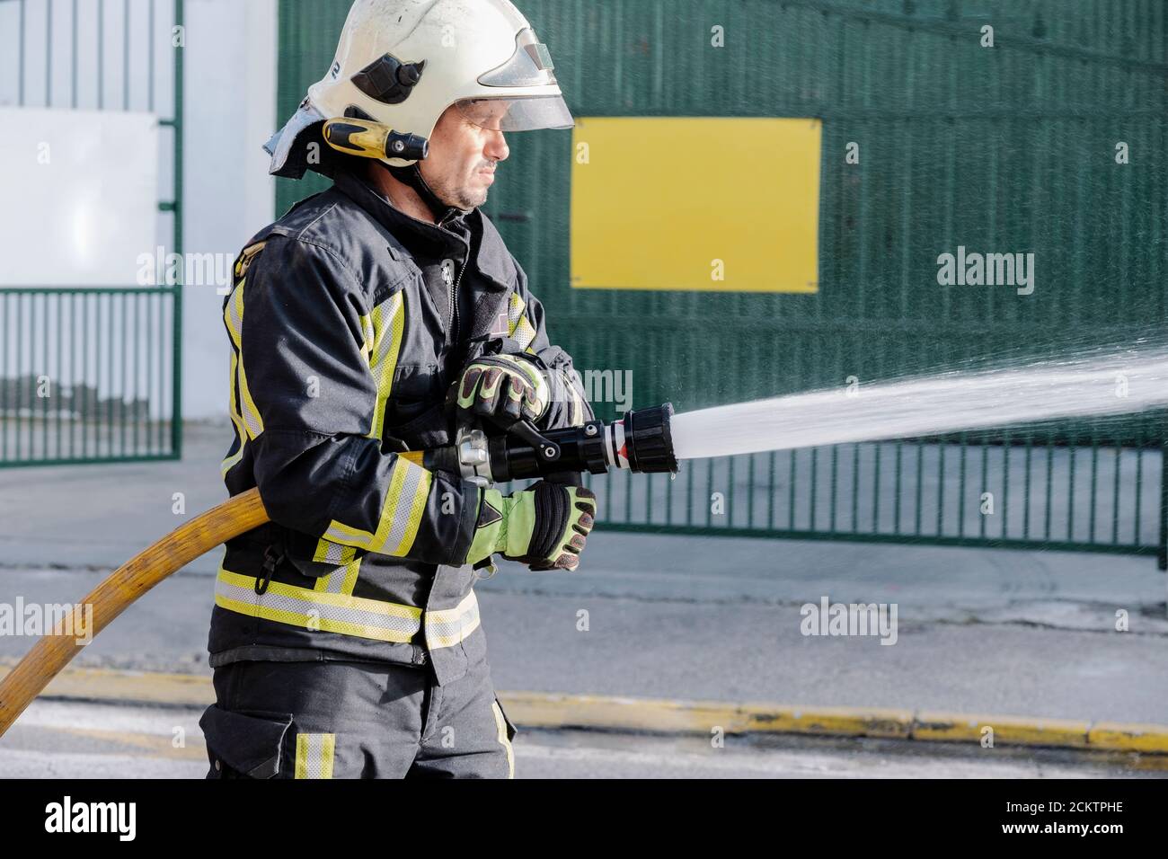 Nahaufnahme eines Feuerwehrmans mit einem Schlauch, der Wasser einstreut Ein Feuer Stockfoto