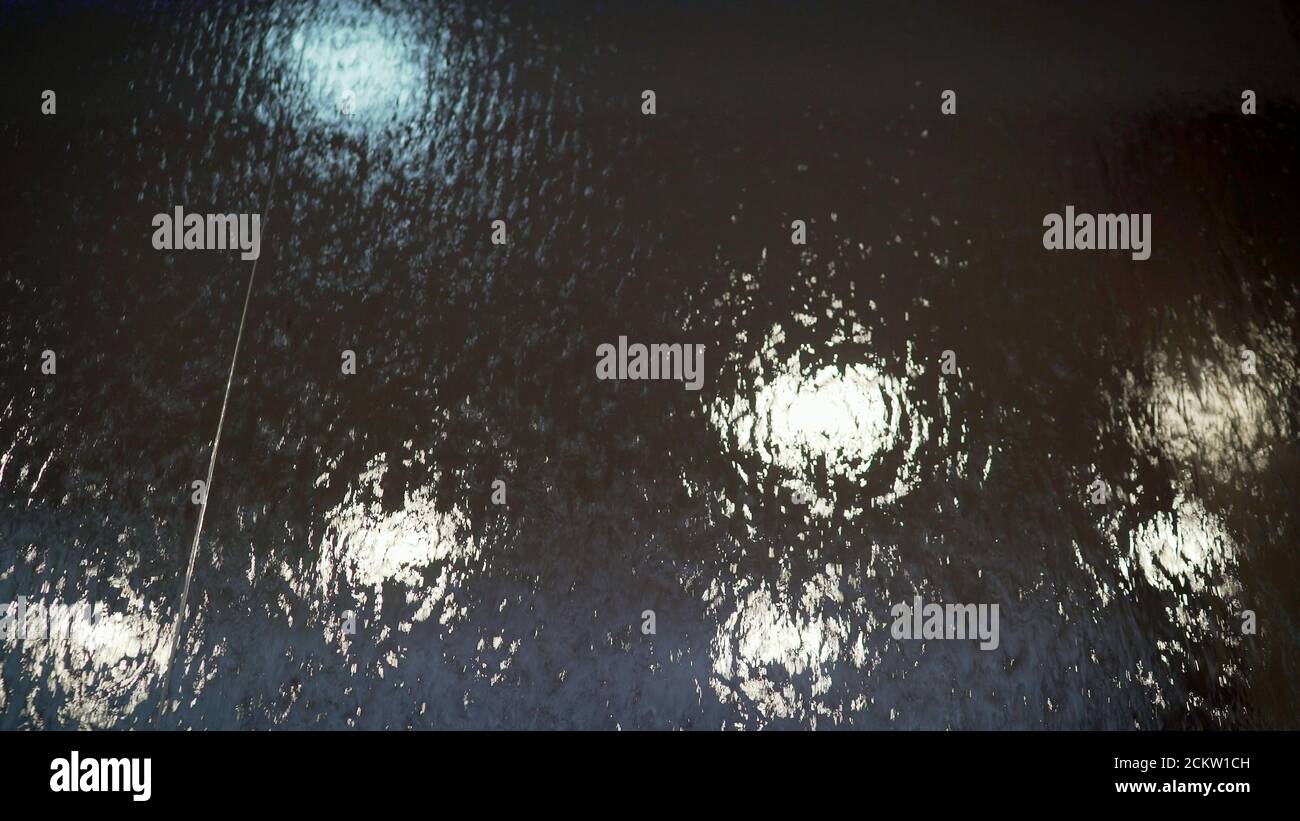 Elite Aquarium System in der Hotellobby. Wasserfälle auf dem Glas. Wasser fließt auf Glas. Nahaufnahme eines dekorativen Wasserfalls hinter Milchglas Stockfoto