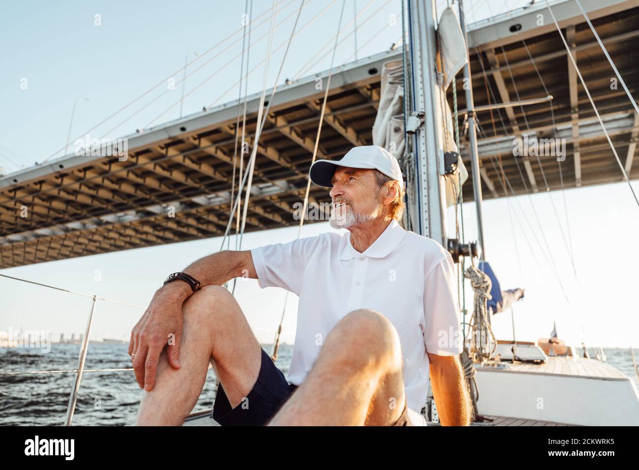 Reifer Mann schaut weg, während er auf seinem Segelboot sitzt Stockfoto