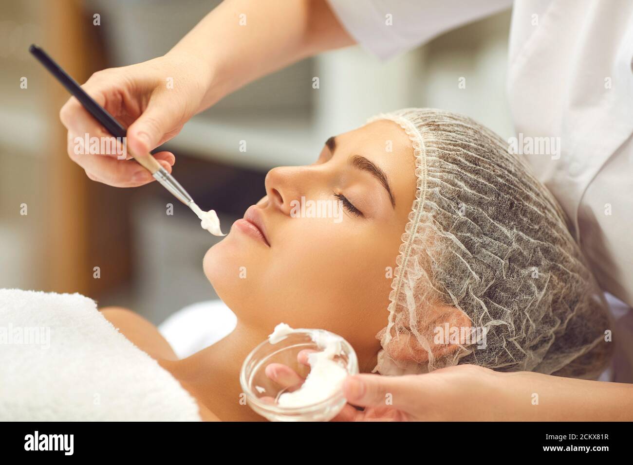 Hände von Dermatologen Putting feuchtigkeitsspendende Creme auf Frauen Gesicht während Hautpflege Verfahren im Spa Salon Stockfoto