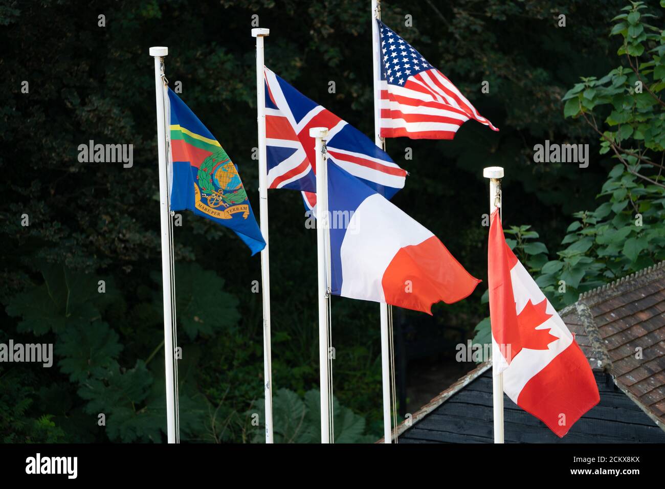 Fünf internationale Flaggen, die auf den Pfählen fliegen, darunter Union Jack, amerikanische, französische und kanadische Flaggen Stockfoto