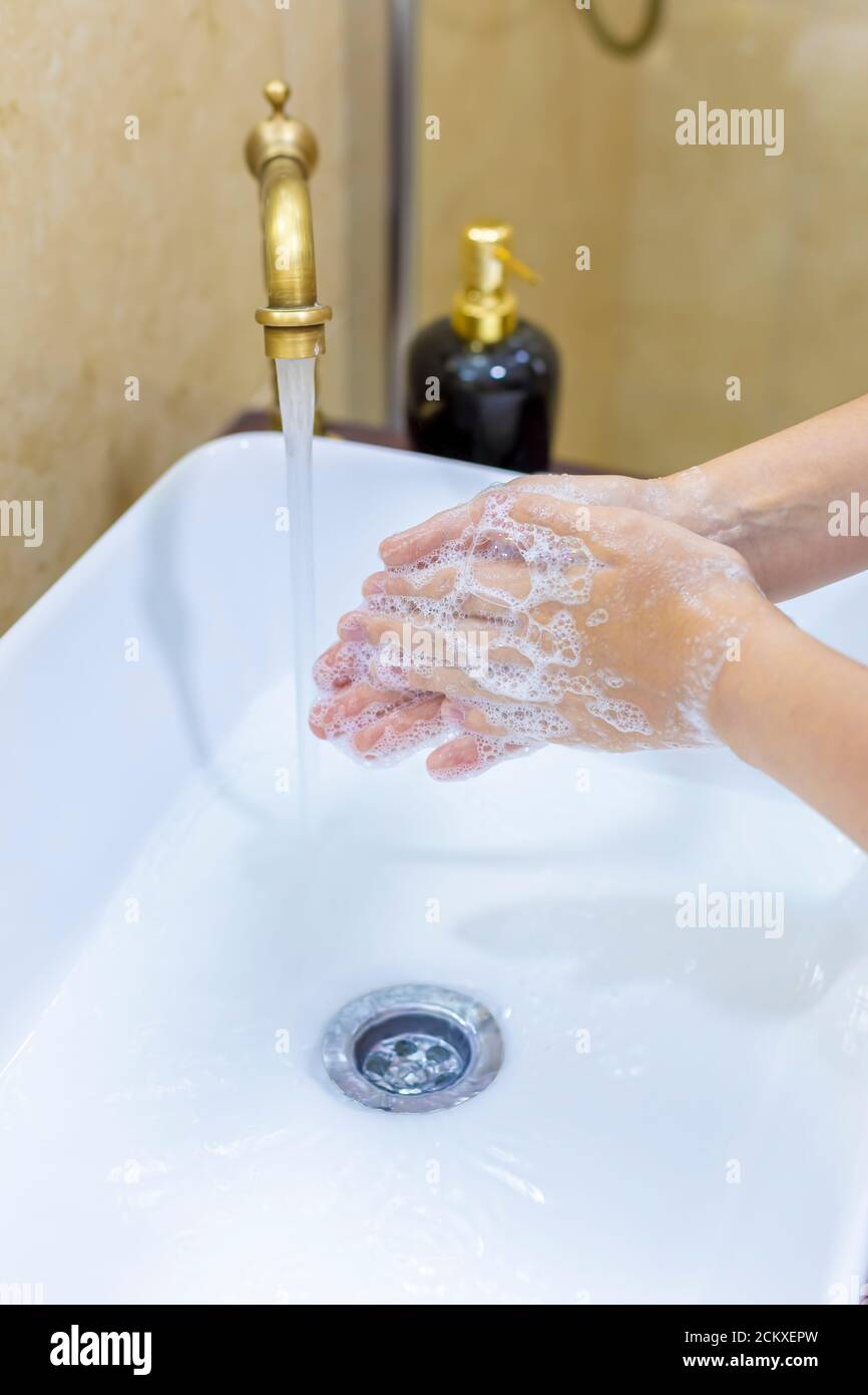 Frau waschen und desinfizieren Hände mit Seife und heißem Wasser als Teil der Coronavirus Prävention und Schutz Protokolle; aufhören zu verbreiten covid-19 Hygiene Stockfoto