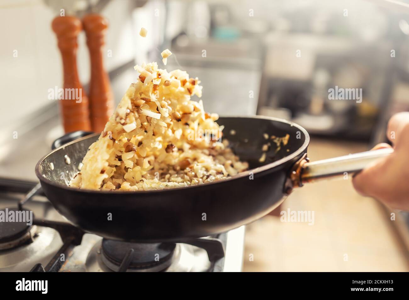 Zwiebeln und Speck in einer Pfanne in der Küche geworfen. Khichri warf sich in eine Wok-Pfanne Stockfoto