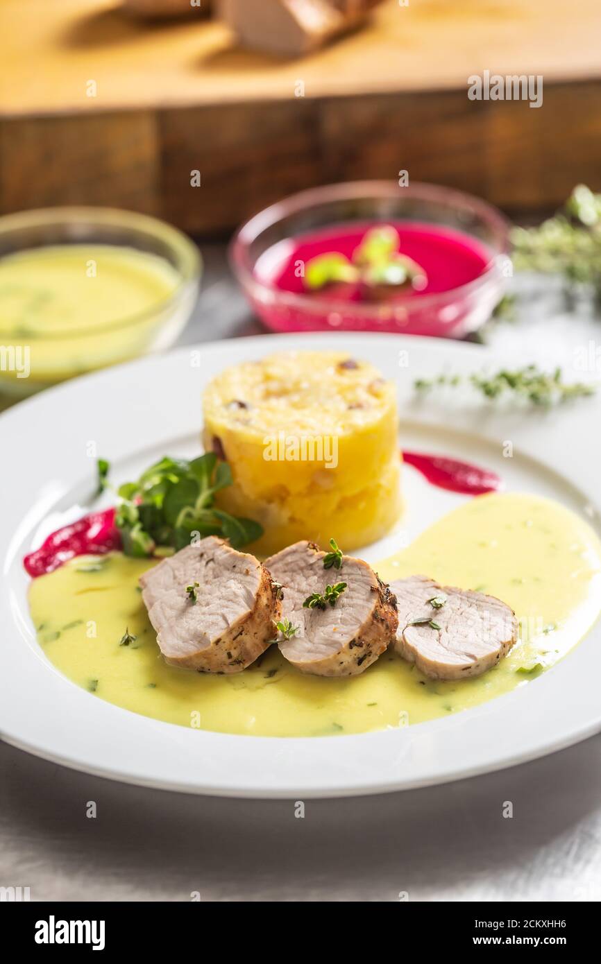 Fleischscheiben und Kartoffelpüree auf einem Teller serviert Mit einer Sauce und Chilis Stockfoto