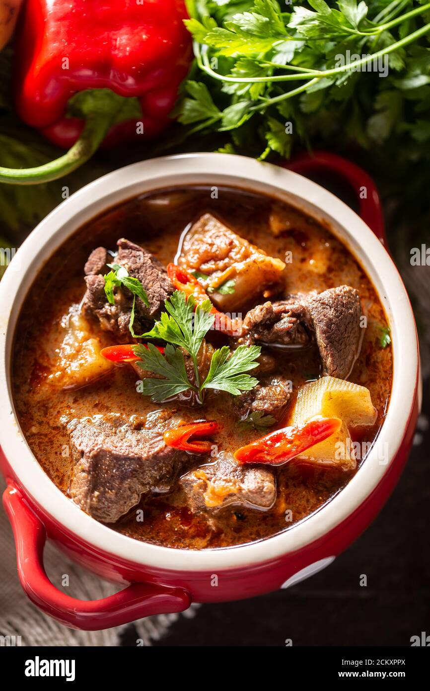 Schüssel Gulaschsuppe mit Fleisch, Kartoffeln, Chilis und Petersilie Stockfoto