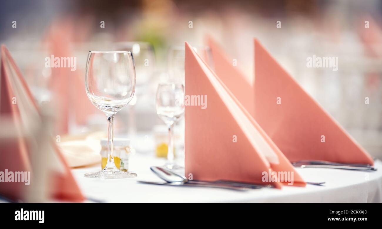 Rosa Servietten gefaltet auf einem festlichen Tisch mit Glaswaren und Besteck daneben Stockfoto