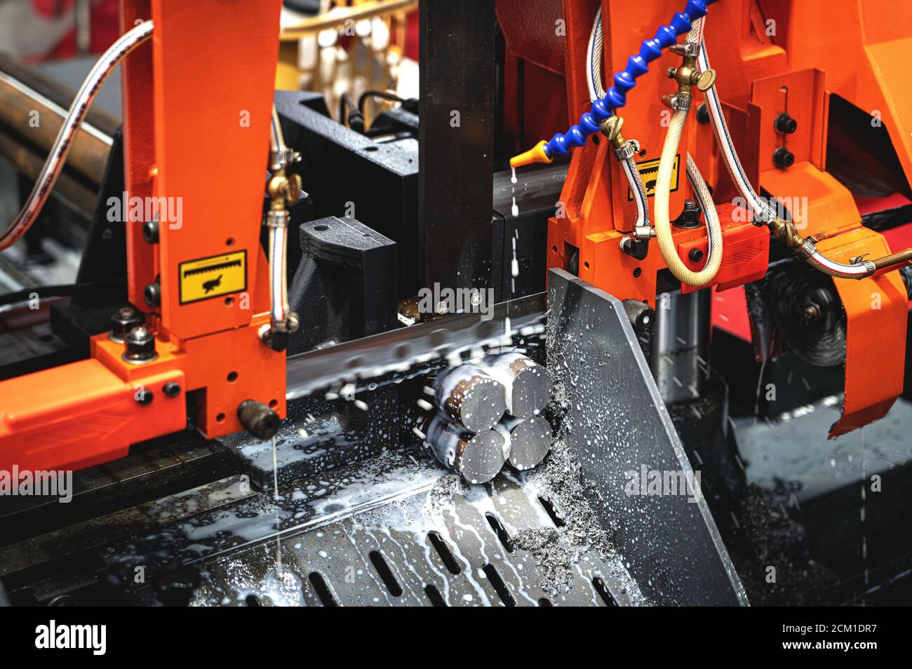 Industrielle Metall-Stangenschneidprozess von CNC-Maschinen mit hochpräzisen elektrischen Sägen und Kühlmitteln. Stockfoto