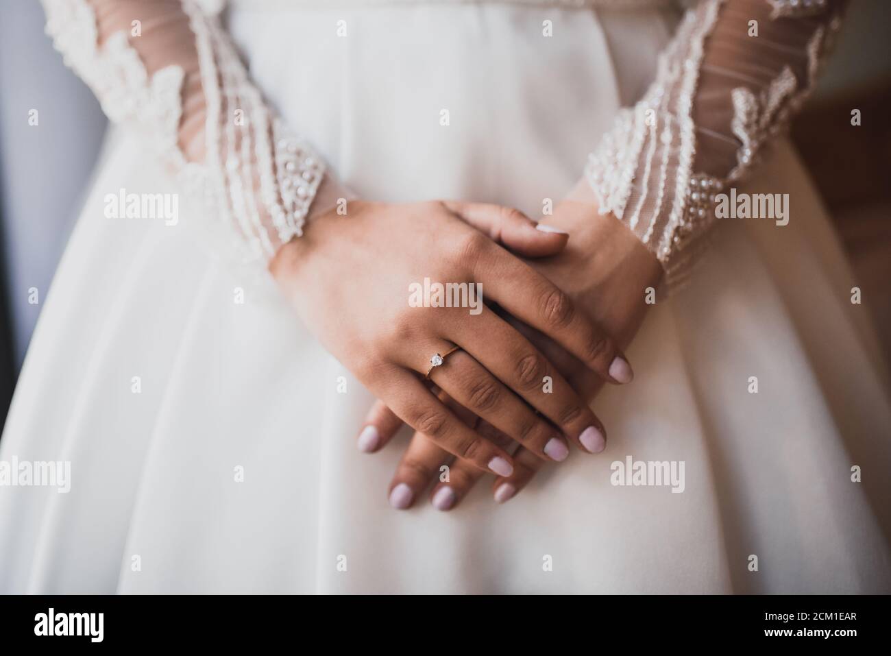 Die weiblichen Hände der hellhäutigen Braut liegen auf dem Weißes Hochzeitskleid Stockfoto