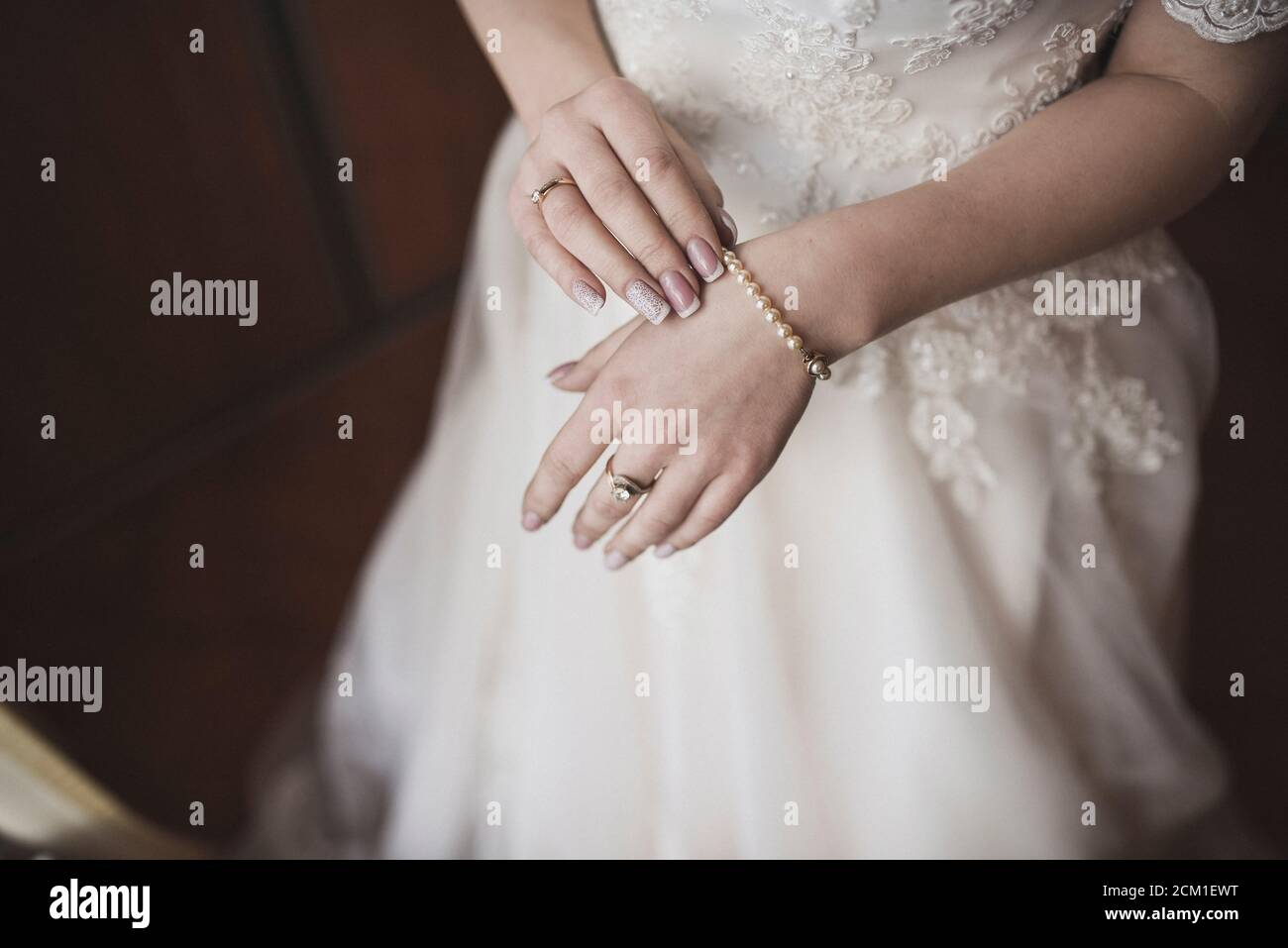 Die weiblichen Hände der hellhäutigen Braut liegen auf dem Weißes Hochzeitskleid Stockfoto