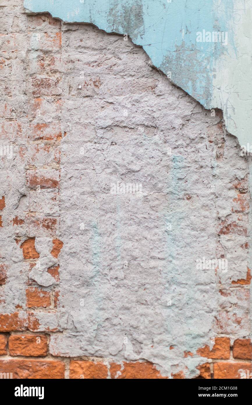 Alte raue rote Ziegelwand mit Gips und Farbe Herunterfallen Stockfoto