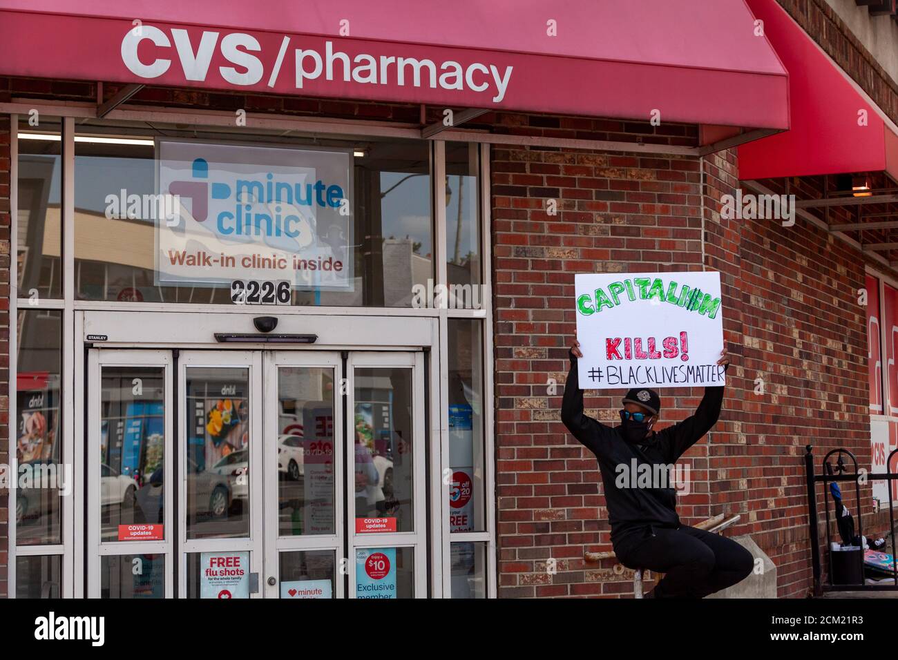 Washington, DC, USA, 16. September 2020. Im Bild: Ein Protestler hält ein Schild am Eingang eines CVS-Ladens, auf dem steht: 'Kapitalismus tötet' ein Hinweis auf die Entscheidung des Managers, den Kunden das Inventar vor das Leben zu stellen. Der Protest fand statt, weil am Tag zuvor der CVS-Store-Manager die Polizei wegen zweier schwarzer Männer anrief. Sechs Polizisten der Metropolitan (DC) verhafteten sie, ließen sie aber frei, nachdem bei einer Durchsuchungsstelle keine gestohlenen Gegenstände gefunden wurden. Angesichts des erheblichen Risikos von Gewalt, wenn die Polizei auf schwarze Männer gerufen werden, kamen Menschen, um gegen die Entscheidung des Managers zu protestieren. Kredit: Allison C Bailey/Alamy Live Nachrichten Stockfoto