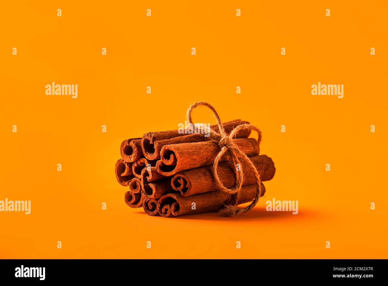 Zimtstangen gebunden mit Jute Seil auf orangefarbenem Hintergrund Stockfoto