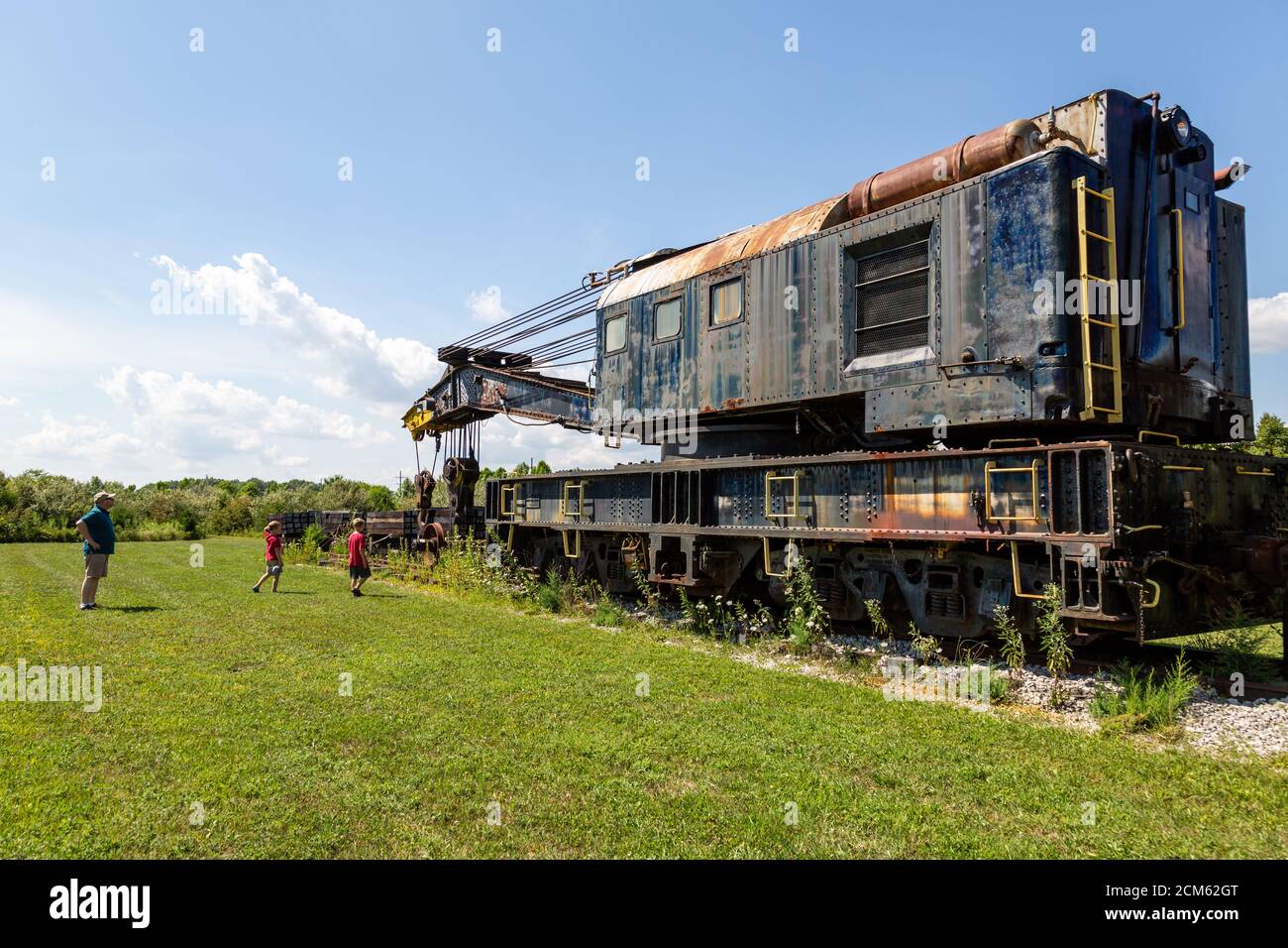 Ein Mann und zwei Jungen schauen sich einen antiken Kranwagen an, der auf den Gleisen vor der Fort Wayne Railroad Historical Society in New Haven, Indiana, USA, sitzt. Stockfoto