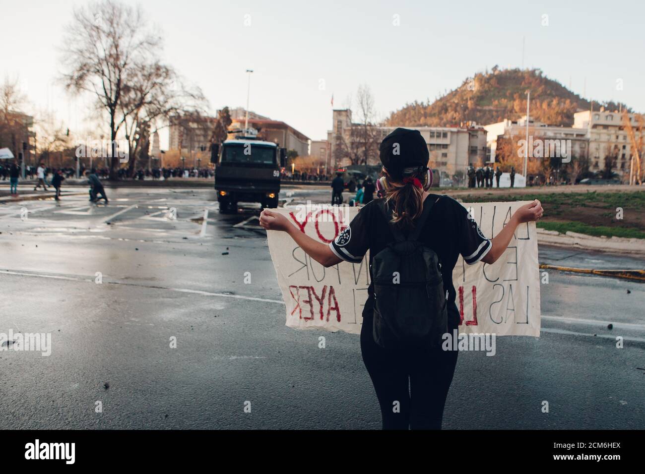 SANTIAGO, CHILE - 11. SEPTEMBER 2020 - EINE junge Frau protestiert mit einem Schild neben einem Polizeifahrzeug. Hunderte von Menschen kamen auf die Plaza Baquedano zu Stockfoto