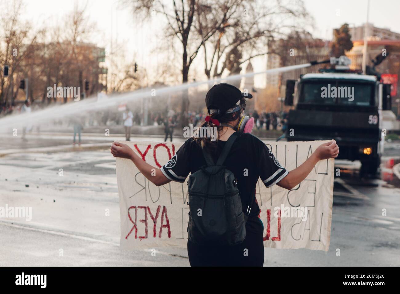 SANTIAGO, CHILE - 11. SEPTEMBER 2020 - EINE junge Frau protestiert mit einem Schild neben einem Polizeifahrzeug. Hunderte von Menschen kamen auf die Plaza Baquedano zu Stockfoto