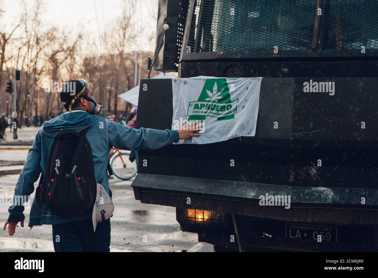 SANTIAGO, CHILE - 11. SEPTEMBER 2020 - EIN Protestler setzt eine Flagge der APRUEBO-Option (ich stimme zu) für eine neue Verfassung auf eine Polizeiwasserkanone. Hu Stockfoto