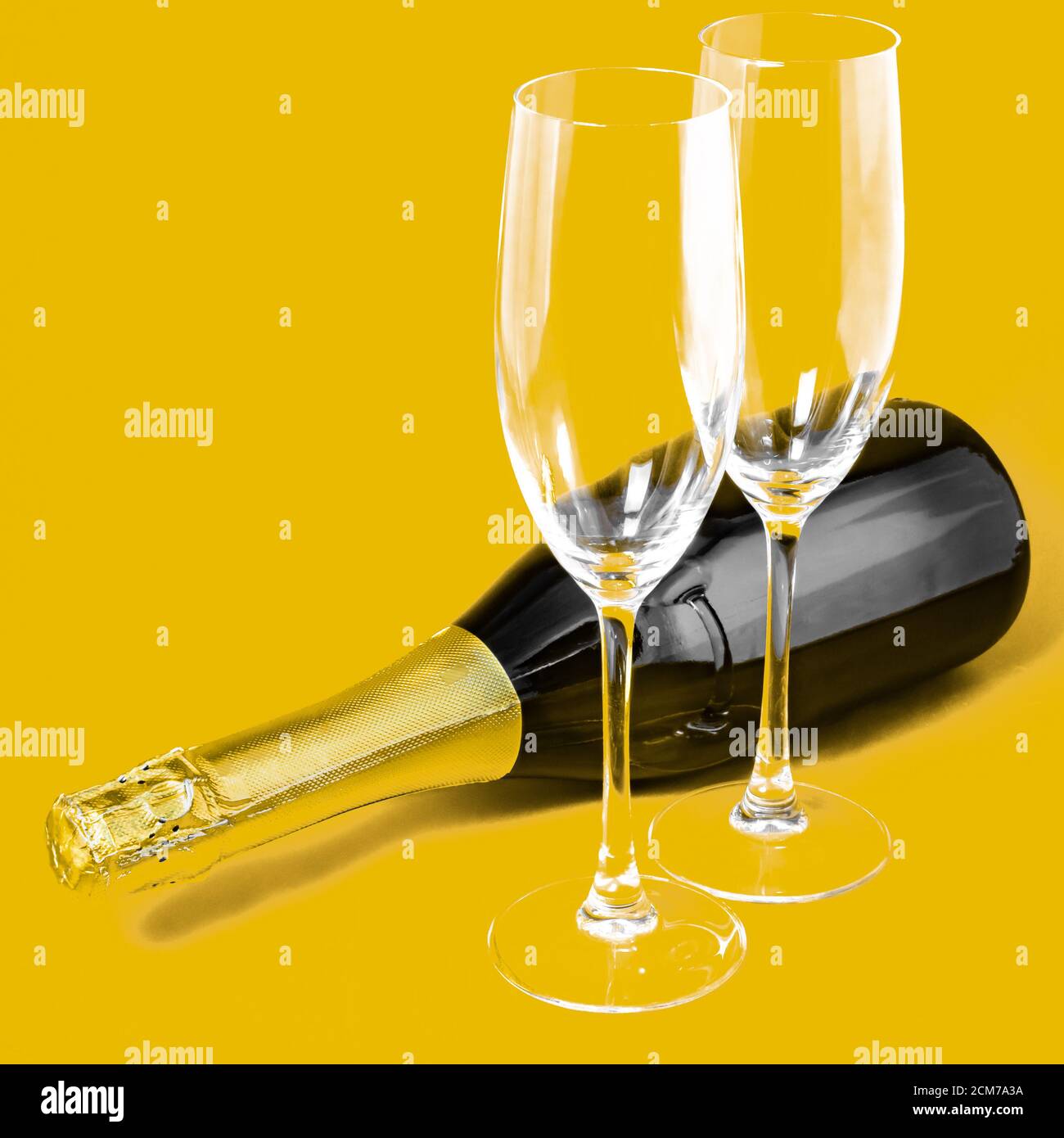 Zwei Sektgläser und eine Flasche auf gelbem Hintergrund Stockfoto