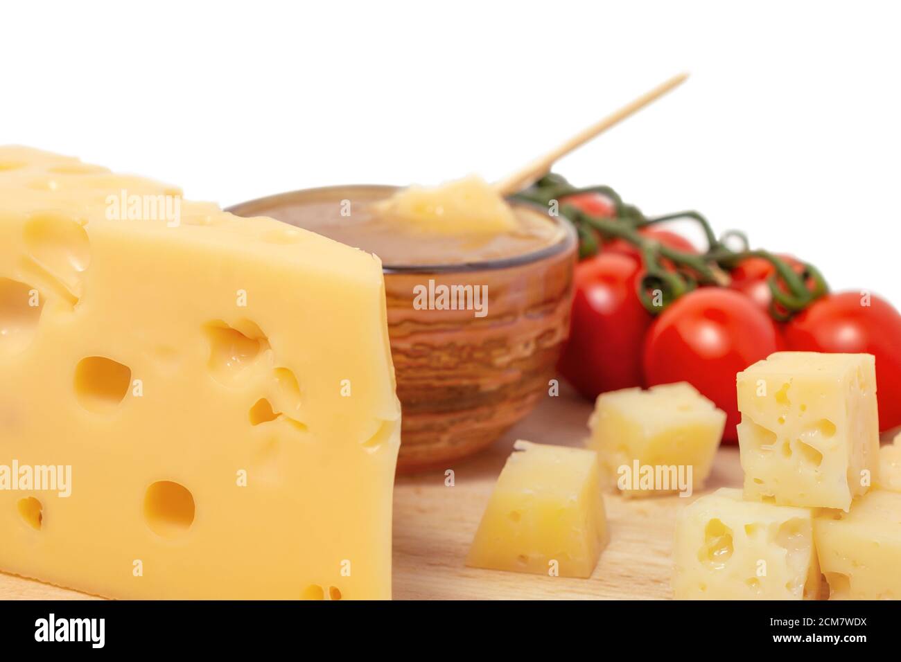 Gelber Maasdam-Käse, dreieckiger Käse mit Löchern, Untertasse mit Honig, Tomatenholz isoliert weißen Hintergrund Stockfoto