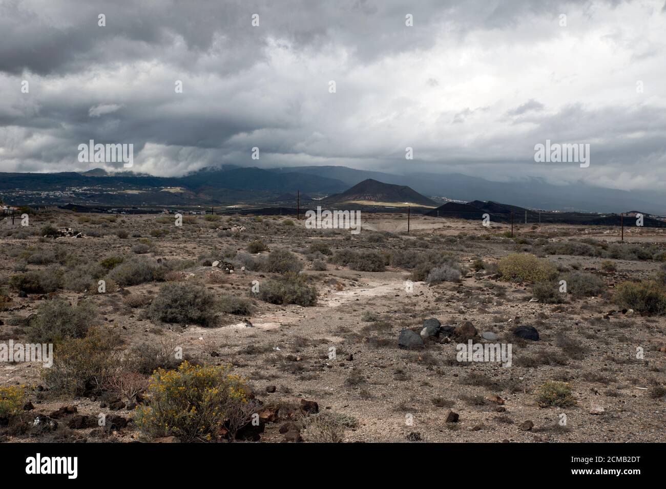 Trockenes und felsiges Gelände mit dunkler Wolkenbildung über den vulkanischen Bergen und Hügeln, seltenes ominöses Wetter vor einem Sturm oder heftigen Regen, Teneriffa Stockfoto