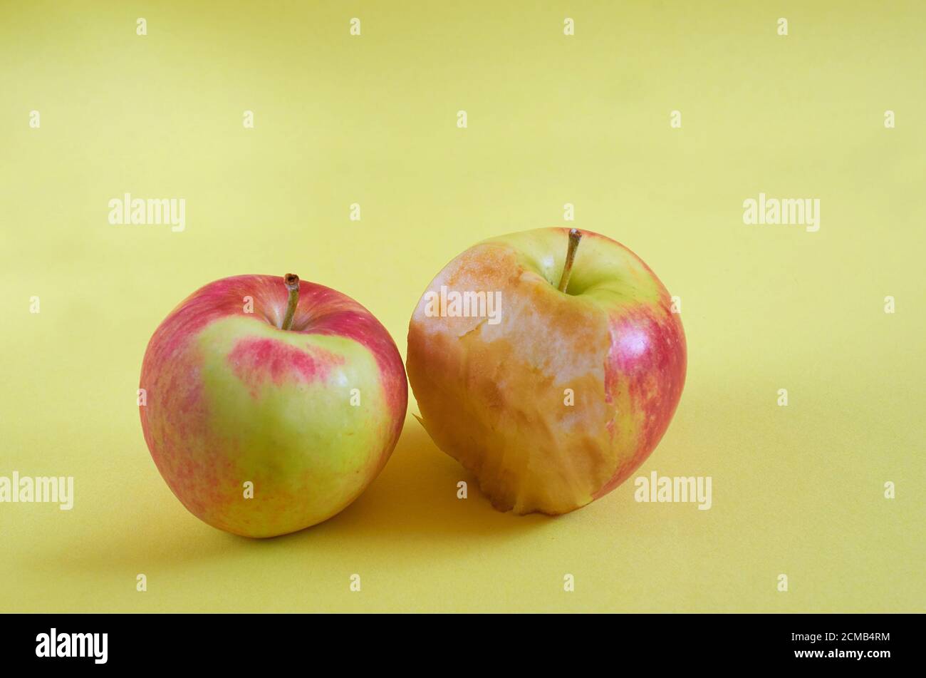 Ein ganzer Apfel und ein gebissene Apfel liegen auf einem farbigen Hintergrund. Nahaufnahme Stockfoto