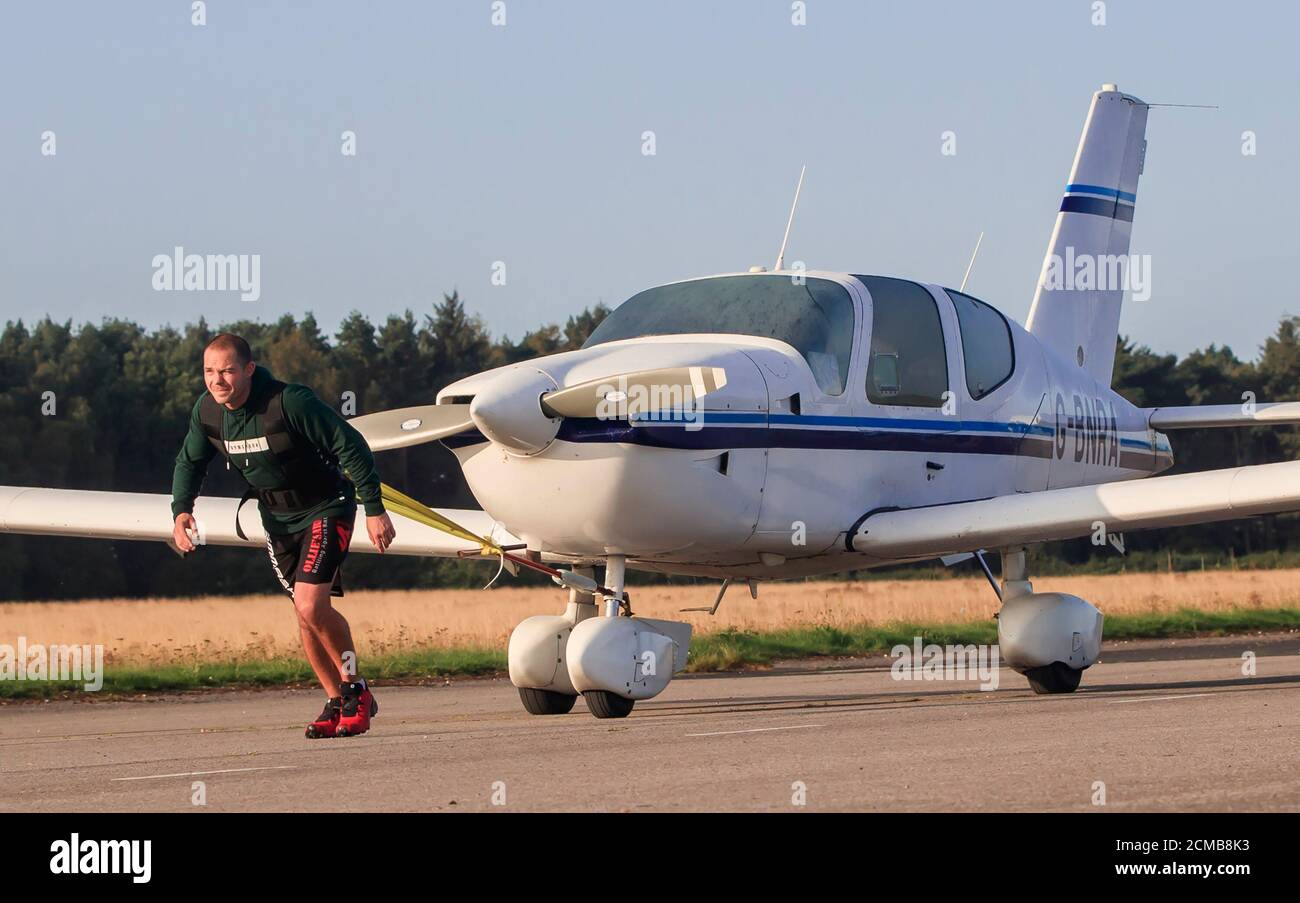 Kickboxen-Weltmeister Carl Thomas bei seinem Versuch, einen Marathon zu laufen, während er am Elvington Airfield bei York ein Flugzeug zieht. Stockfoto