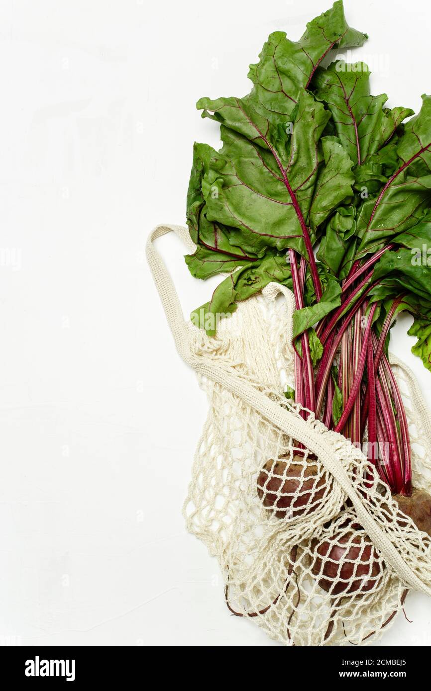 Trendige Saitentasche mit frischer junger Rote Bete und Haul auf hellweißem Hintergrund. Zero Waste nachhaltiges Lifestyle-Konzept. Stockfoto