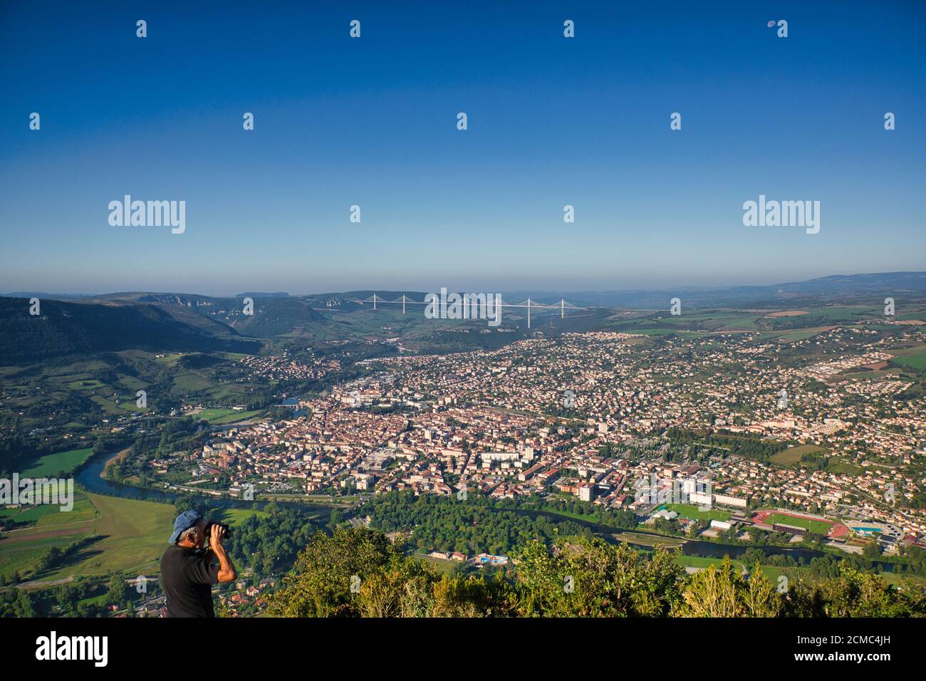 Luftaufnahme über die Stadt Millau mit dem berühmten Viadukt von Millau oder Viaduc de Millau in der Ferne. Ein blauer Himmel über dem Himmel in Aveyron, Frankreich Stockfoto