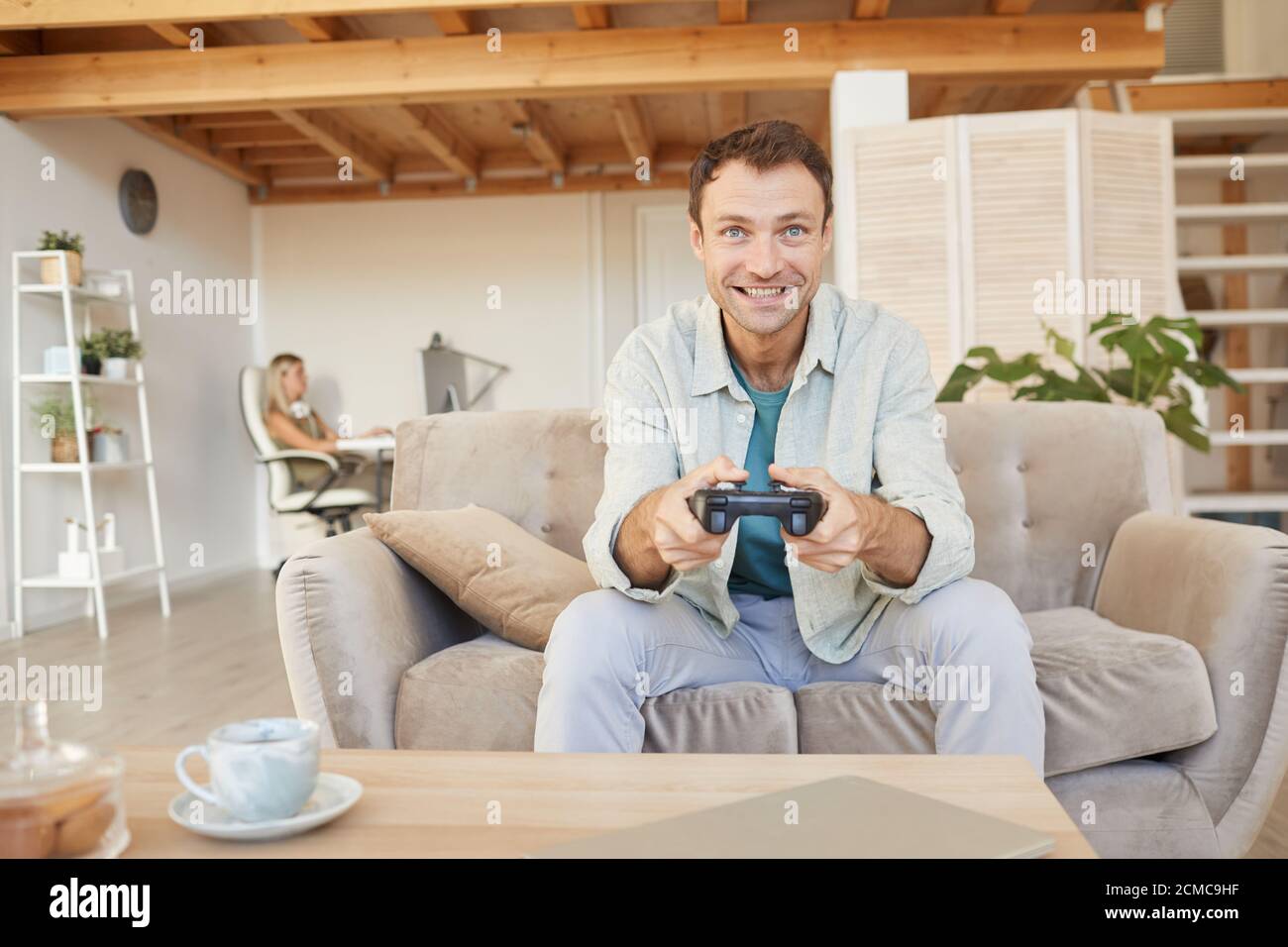 Aufgeregt glücklich Mann sitzt auf dem Sofa mit Joystick und spielen In Computerspielen im Wohnzimmer Stockfoto