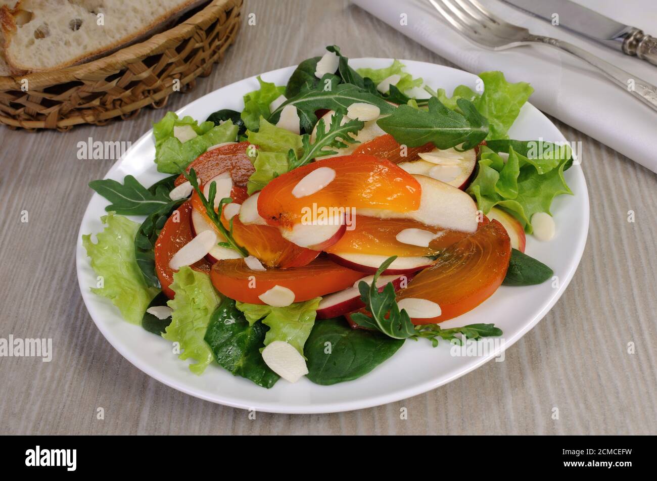 Salatgemüse mit Kaki und Mandeln Stockfoto