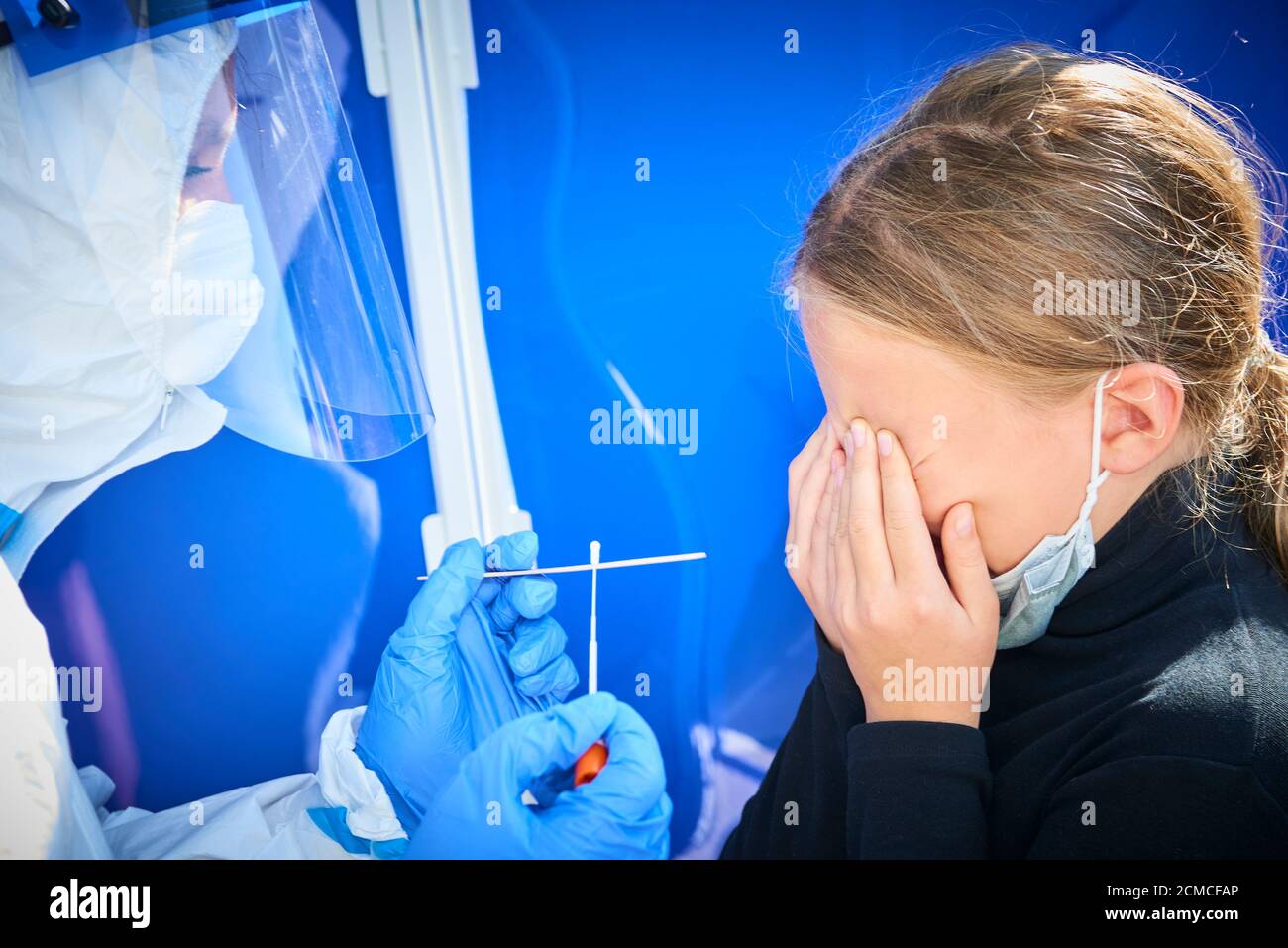 Entnahme einer medizinischen Probe - ein Rachenabstrich für einen Coronavirus-Test. Krankenschwester nimmt eine Probe von Kind blonde Mädchen für Covid 19 Test. Eine unangenehme Erfahrung Stockfoto