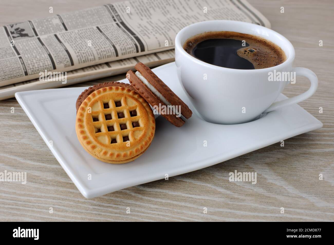 Eine Tasse Kaffee und Kekse und eine Zeitung Stockfoto
