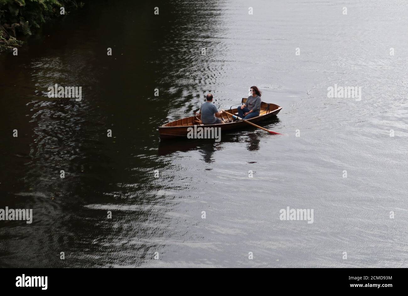 Paar in einem hölzernen Ruderboot mitten im Fluss Stockfoto
