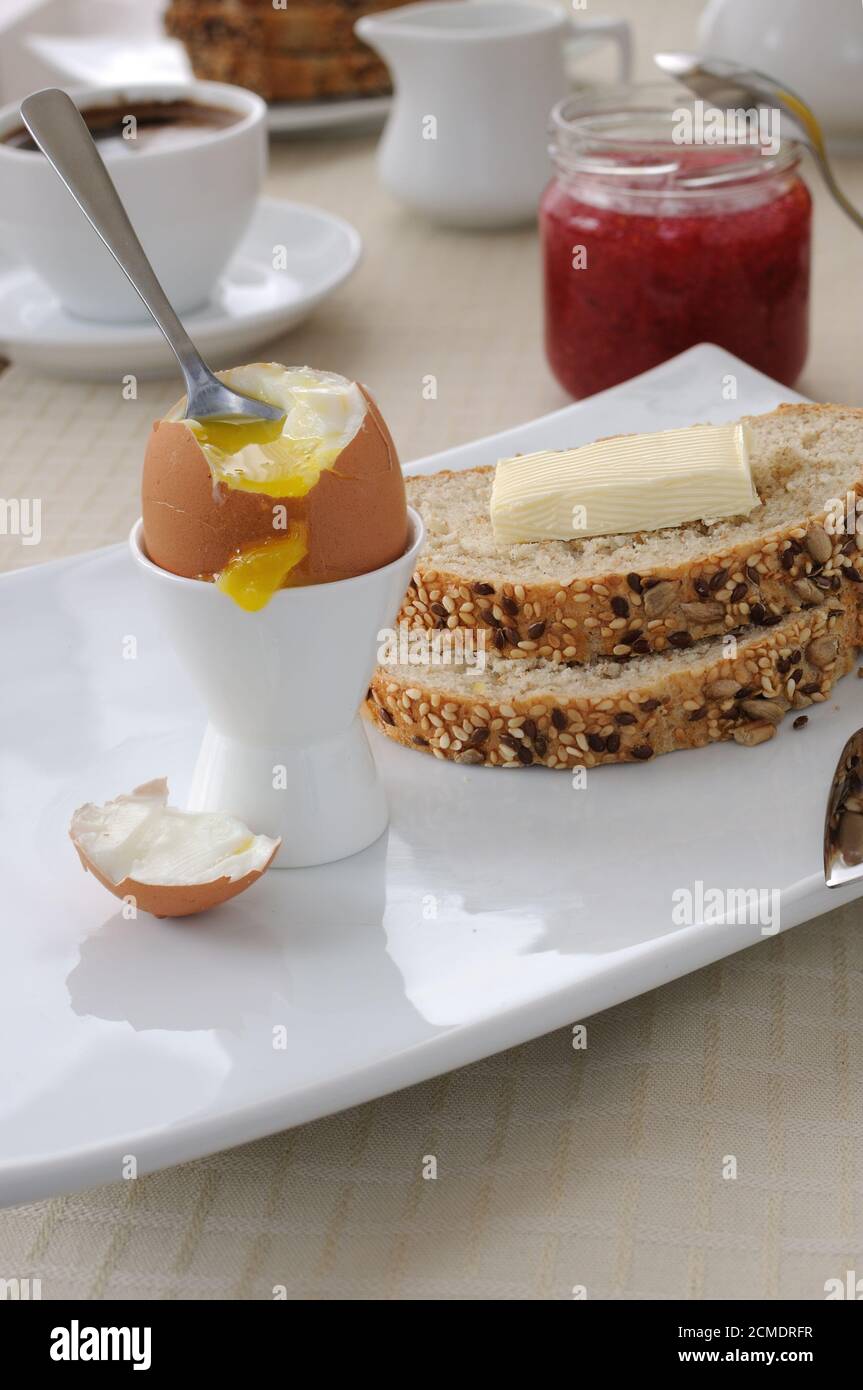 Frühstück mit weich gekochtem Ei und Scheiben Haferflockenbrot Stockfoto