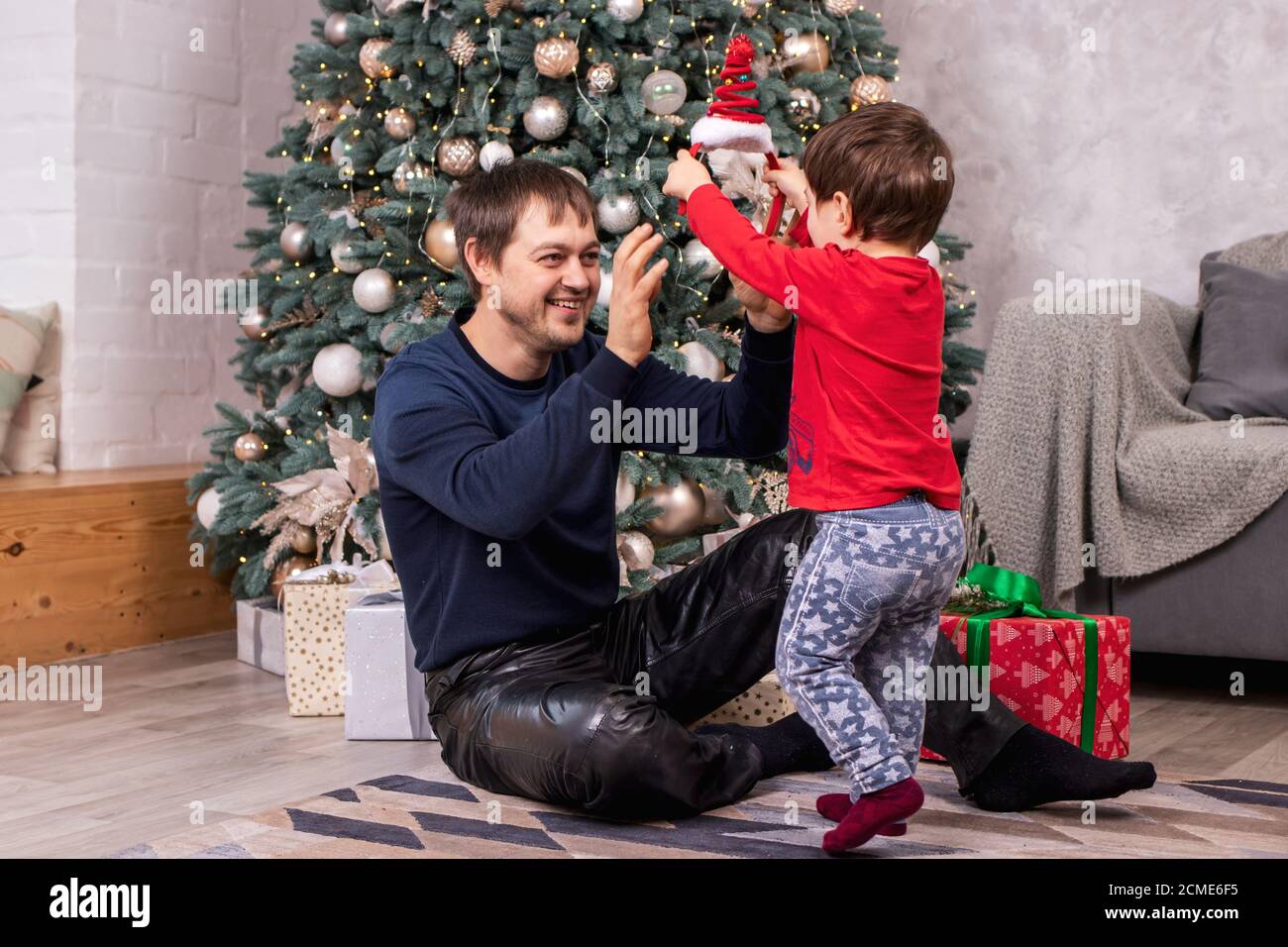 Vater und Sohn haben Spaß, lachen und lächeln rund um den Weihnachtsbaum. Silvester. Stockfoto