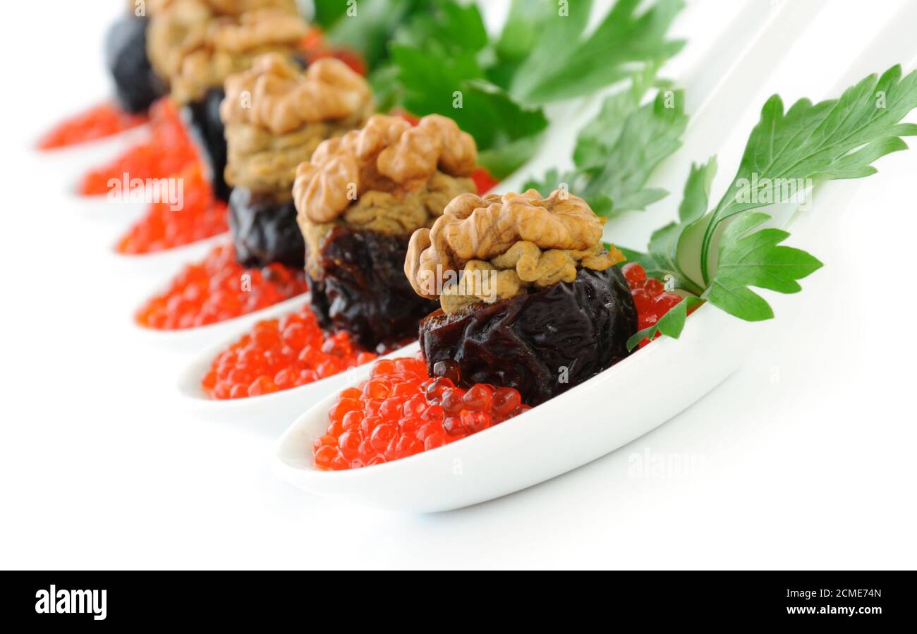 Pflaumen gefüllt mit Leberpastete mit Nüssen in einem rotem Kaviar Stockfoto