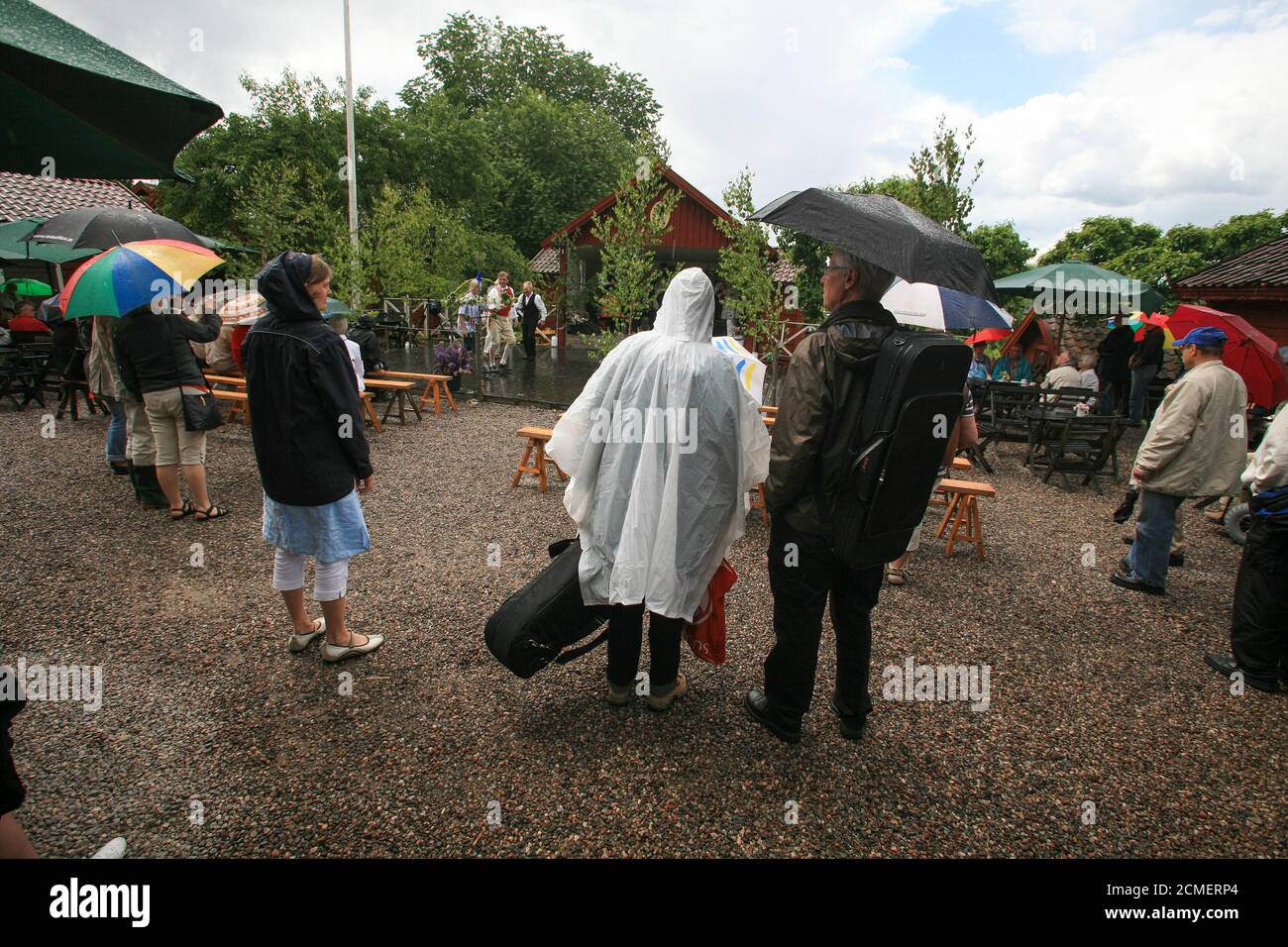 MUSIKER IM REGEN warten im Regen unter Regenkleidung mit Die Instrumente in ihren Fällen Stockfoto