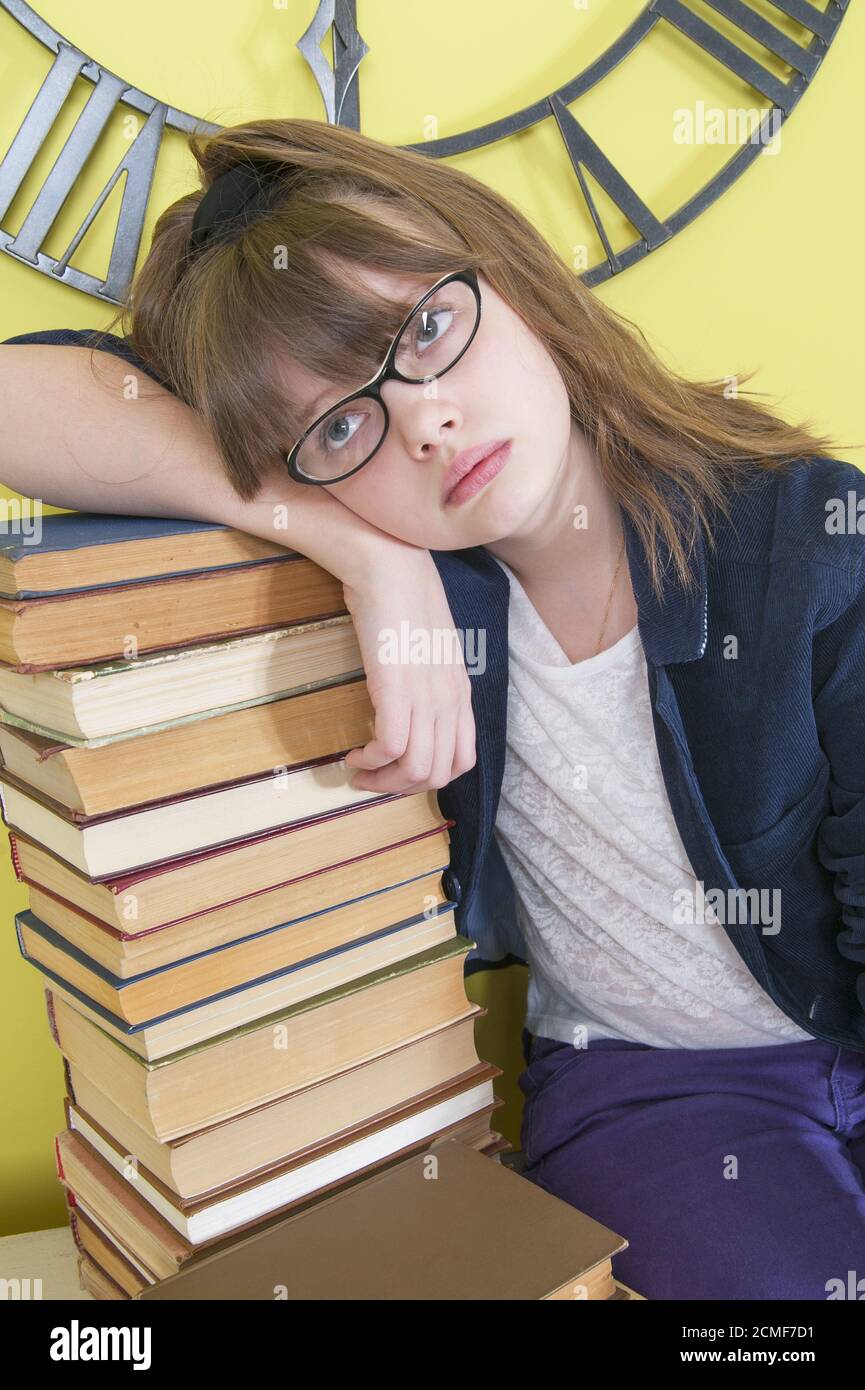 Müde zehn Jahre Mädchen lehnte sich auf einen Stapel von Büchern. Stockfoto