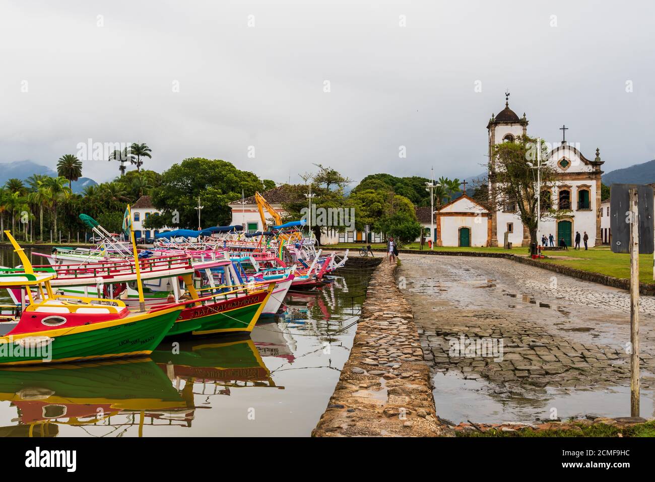 Blick auf den Yachthafen mit den traditionellen brasilianischen Schiffen, die daneben angedockt sind Alte katholische Kirche in einer ländlichen Landschaft Stockfoto